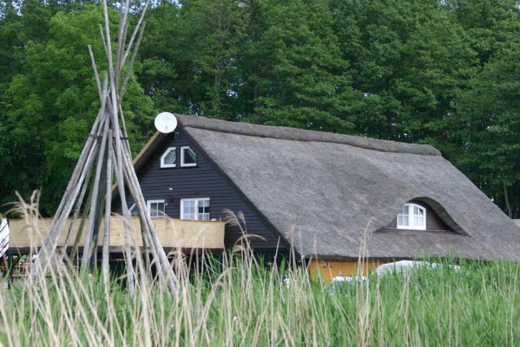 Une maison traditionnelle à toit de chaume, dotée d’une petite fenêtre et d’une structure en bois à l’avant.