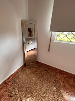 Une chambre avec un lit, un miroir, une fenêtre donnant sur un beau paysage et un tapis tissé.