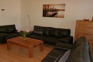 Ein Wohnzimmer mit einer Sofagarnitur, einem Couchtisch und einem Gemälde an der Wand.