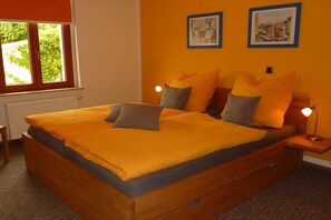 Ein Schlafzimmer mit einem hölzernen Bett, zwei Nachttischlampen und zwei gerahmten Bildern an der Wand.