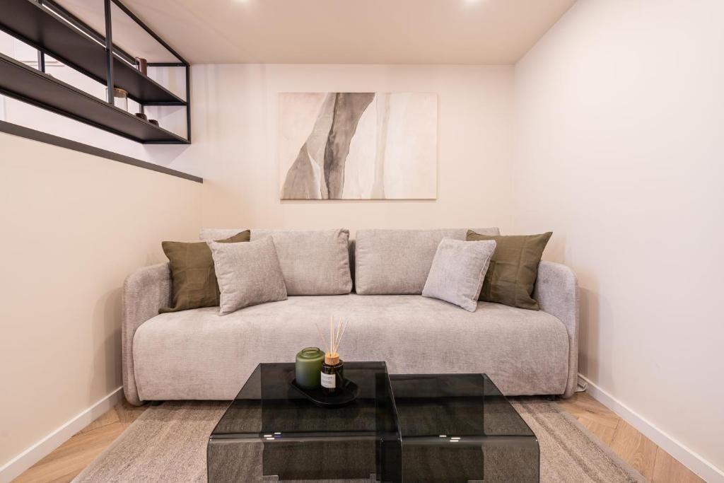 Ein modernes Wohnzimmer mit einem grauen Sofa, einem Glastisch und einem minimalistischen Gemälde an der Wand.