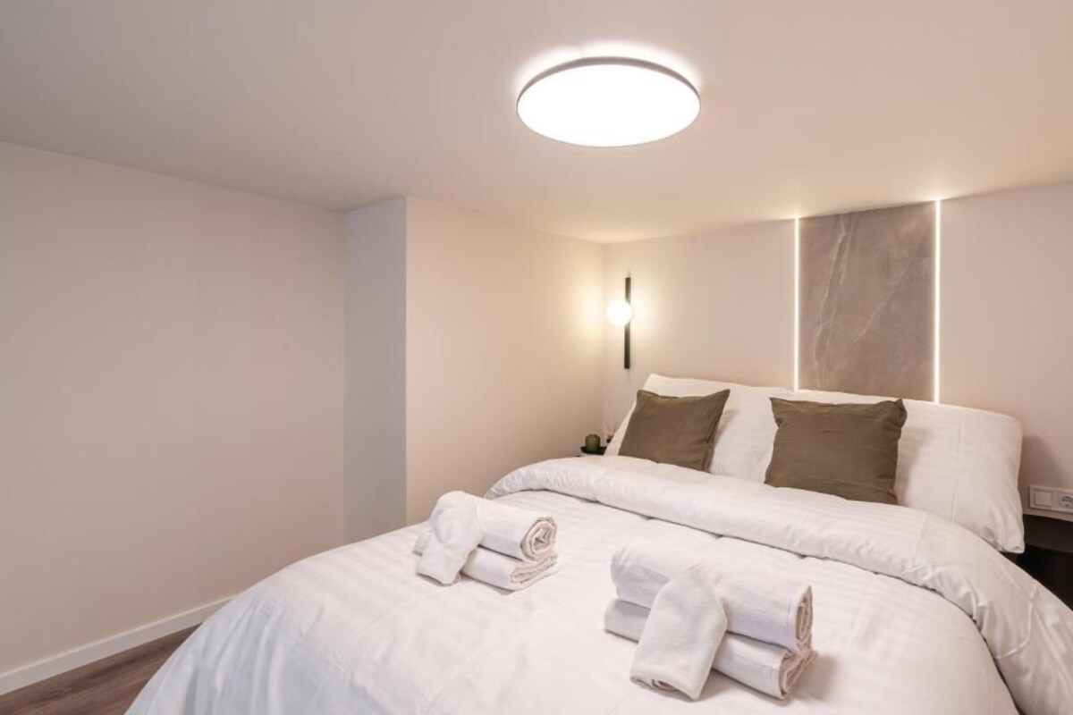 Ein Hotelzimmer mit einem Bett, einer runden Deckenleuchte und einer Wandlampe.