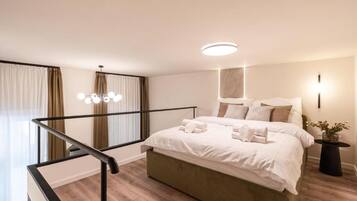 Ein modernes Schlafzimmer mit einem großen Bett, einem Nachttisch, einer Zimmerpflanze und einer Treppe mit Geländer.