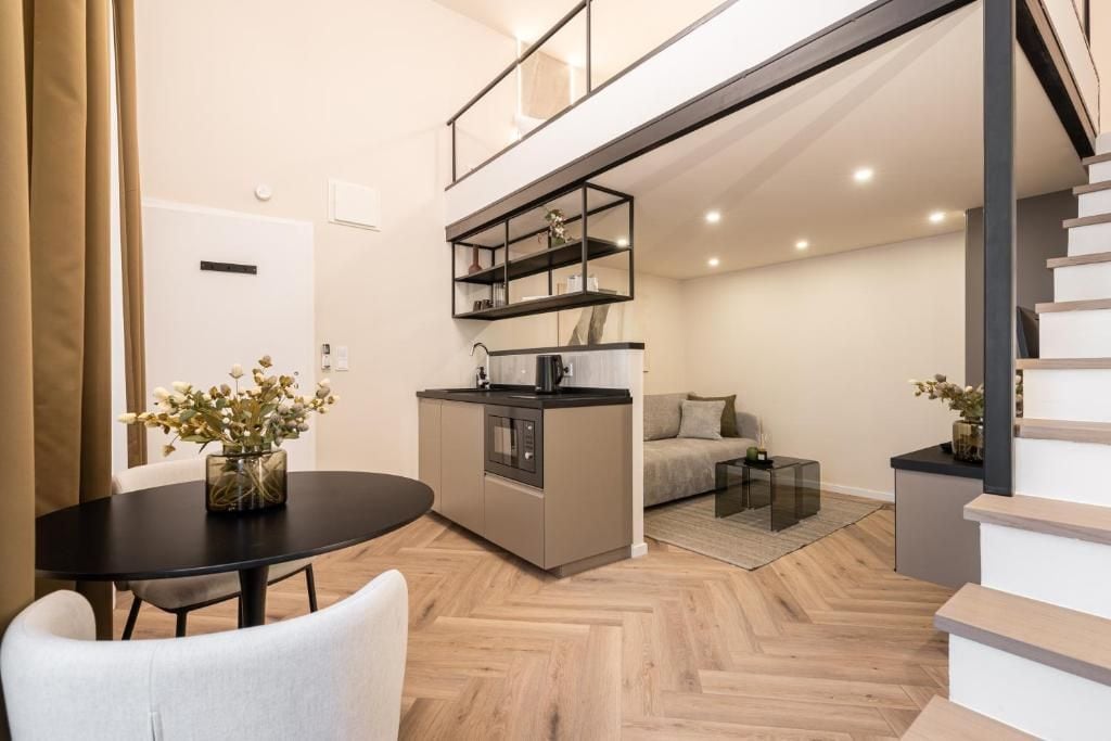 Un appartamento moderno con zona pranzo, angolo cottura, divano e una scala.