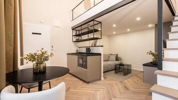 Un appartamento moderno con zona pranzo, angolo cottura, divano e una scala.