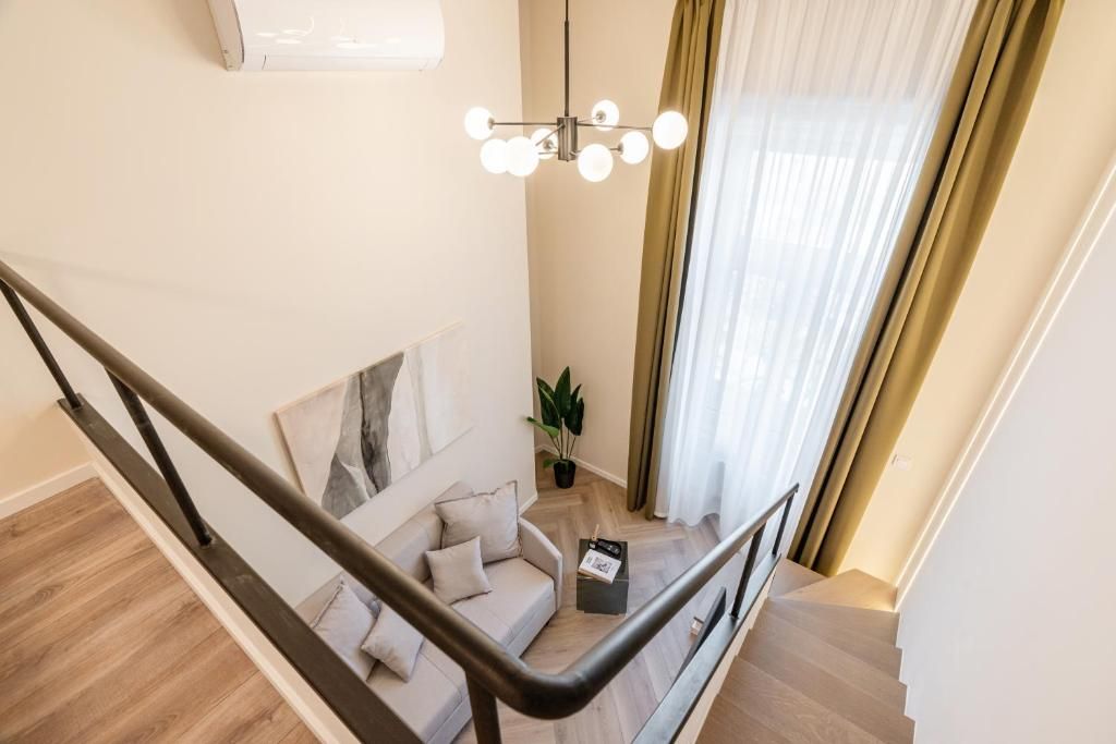 Un interior moderno con una escalera, un sofá, una planta y una lámpara colgante.