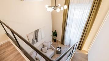 Un interior moderno con una escalera, un sofá, una planta y una lámpara colgante.