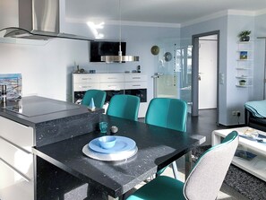 Eine moderne Küche mit schwarzem Arbeitsplatz, Türkis-Stühlen und einem Esstisch.