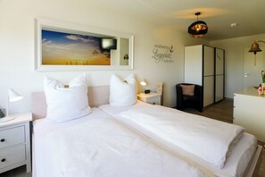 Ein Hotelzimmer mit Bett, Nachttischen, einer Lampe, einem Wandbild, einer Deckenleuchte und einem Kleiderschrank.