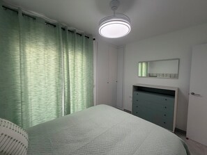 A bedroom with a bed, a dresser, a mirror, and a ceiling light. - Vacation Apartment (Vejer de la Frontera)
