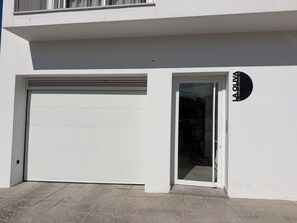 A white building with a closed garage door and a glass door entrance. - Vacation Apartment (Vejer de la Frontera)