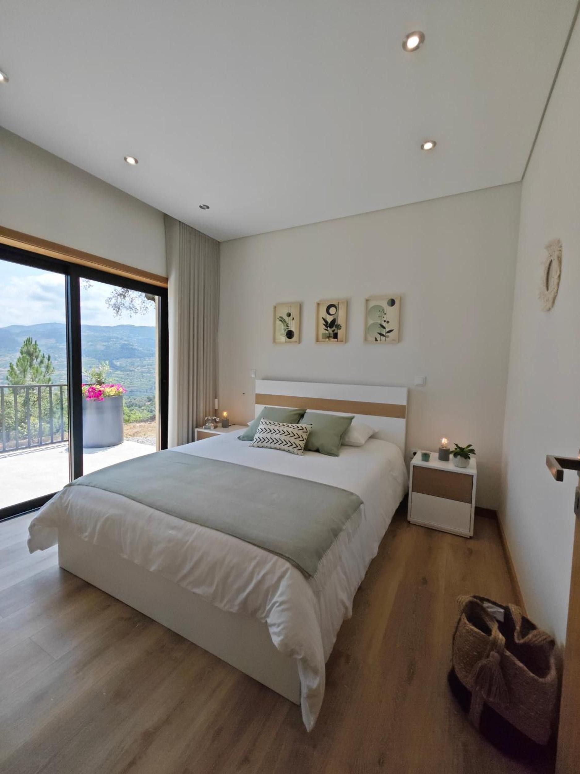 A modern bedroom with a large bed, bedside tables, and artwork on the wall.