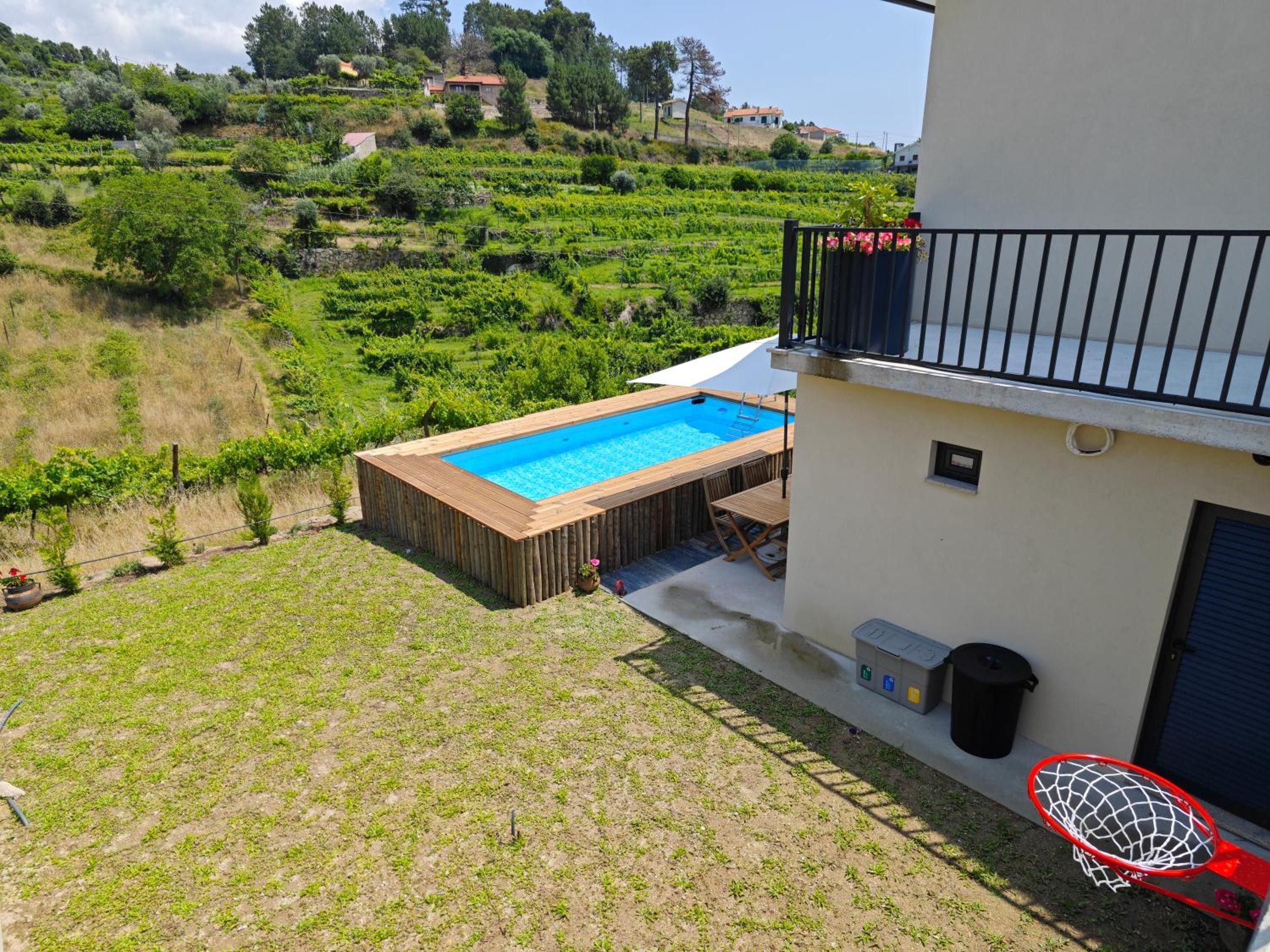 A residential property with a swimming pool, a basketball hoop, and a view of a hilly landscape.