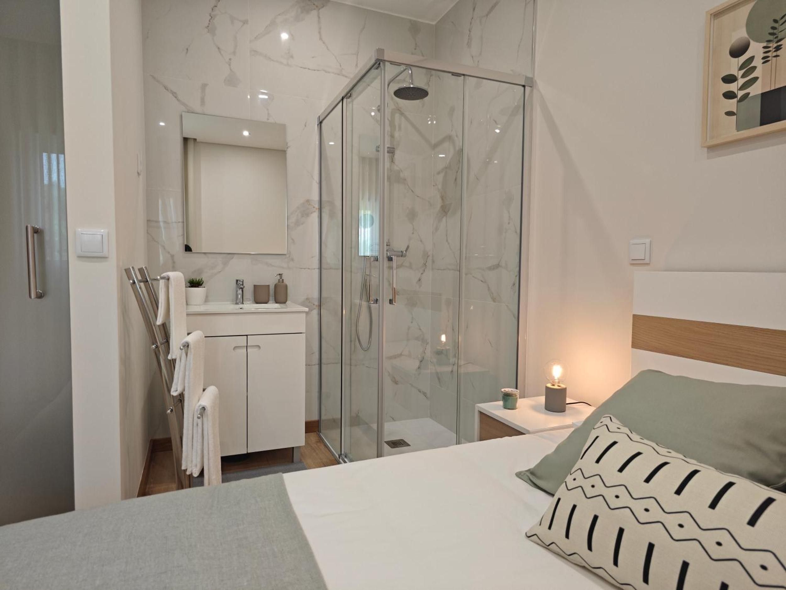 A modern bathroom with a glass shower enclosure, a white vanity, and a mirror above the sink.