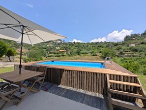 Een houten jacuzzi met uitzicht op een glooiend landschap.