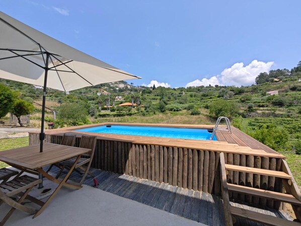 A wooden hot tub with a view of a hillside landscape.