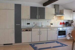 A kitchen with white cabinets, a dishwasher, an oven, and a tiled backsplash. - Holiday apartment with 1 bedroom (Neunkirchen)