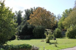 A well-maintained garden with a variety of trees and shrubs, a clear sky, and a paved pathway. - Holiday apartment with 1 bedroom (Neunkirchen)