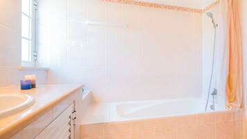 Une salle de bain équipée d’une baignoire, d’une douche et d’un meuble-lavabo avec un miroir.