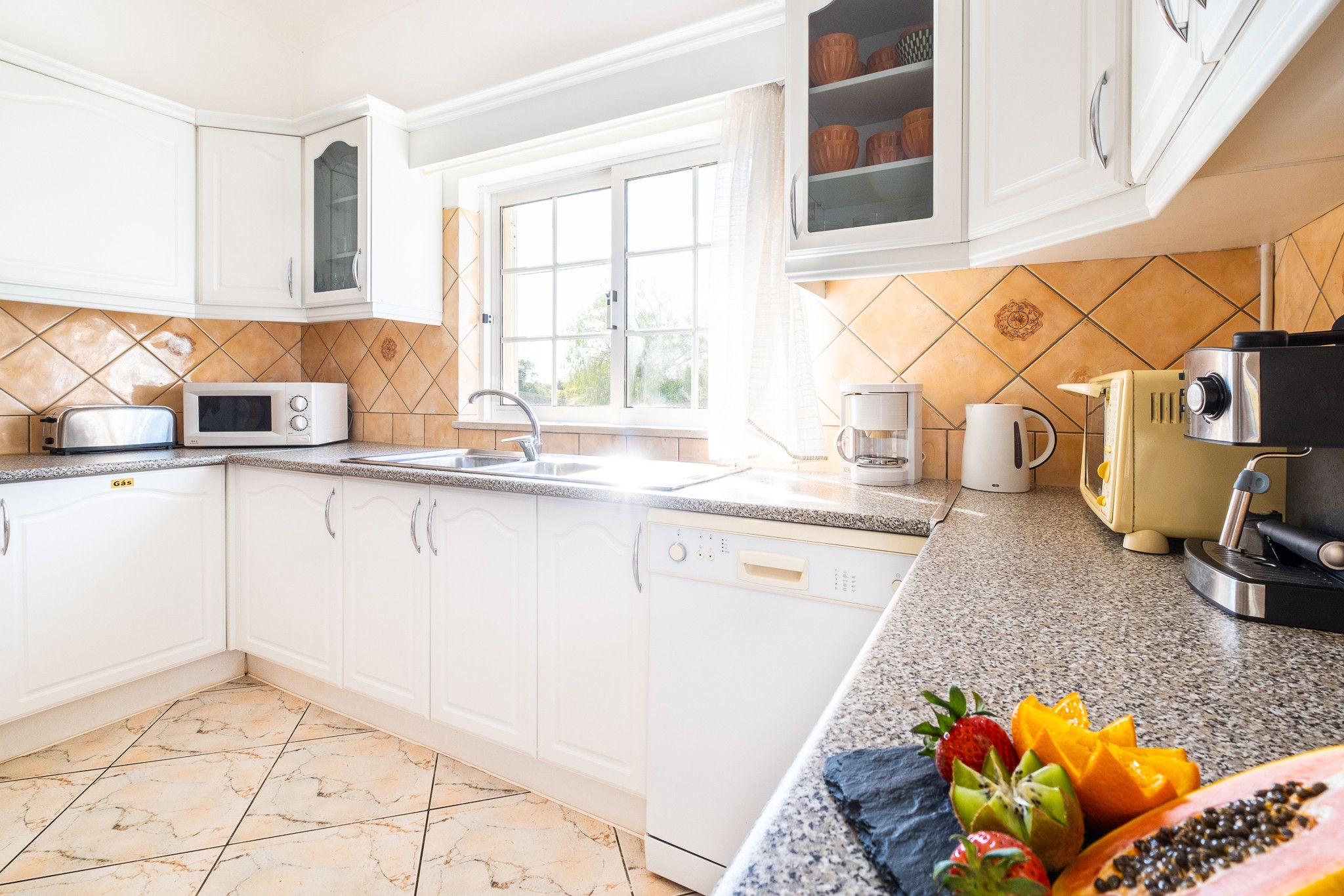 A kitchen with white cabinets, a microwave, a coffee maker, and a toaster.