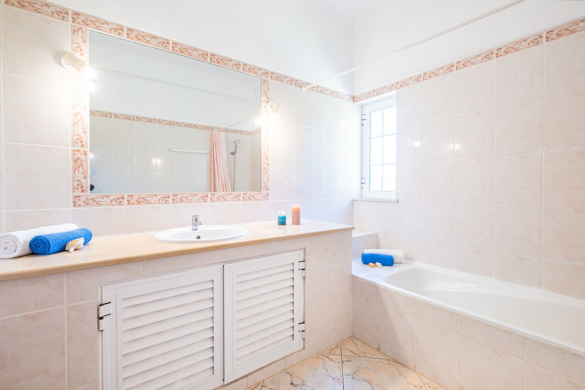 A bathroom with a sink, mirror, and bathtub.