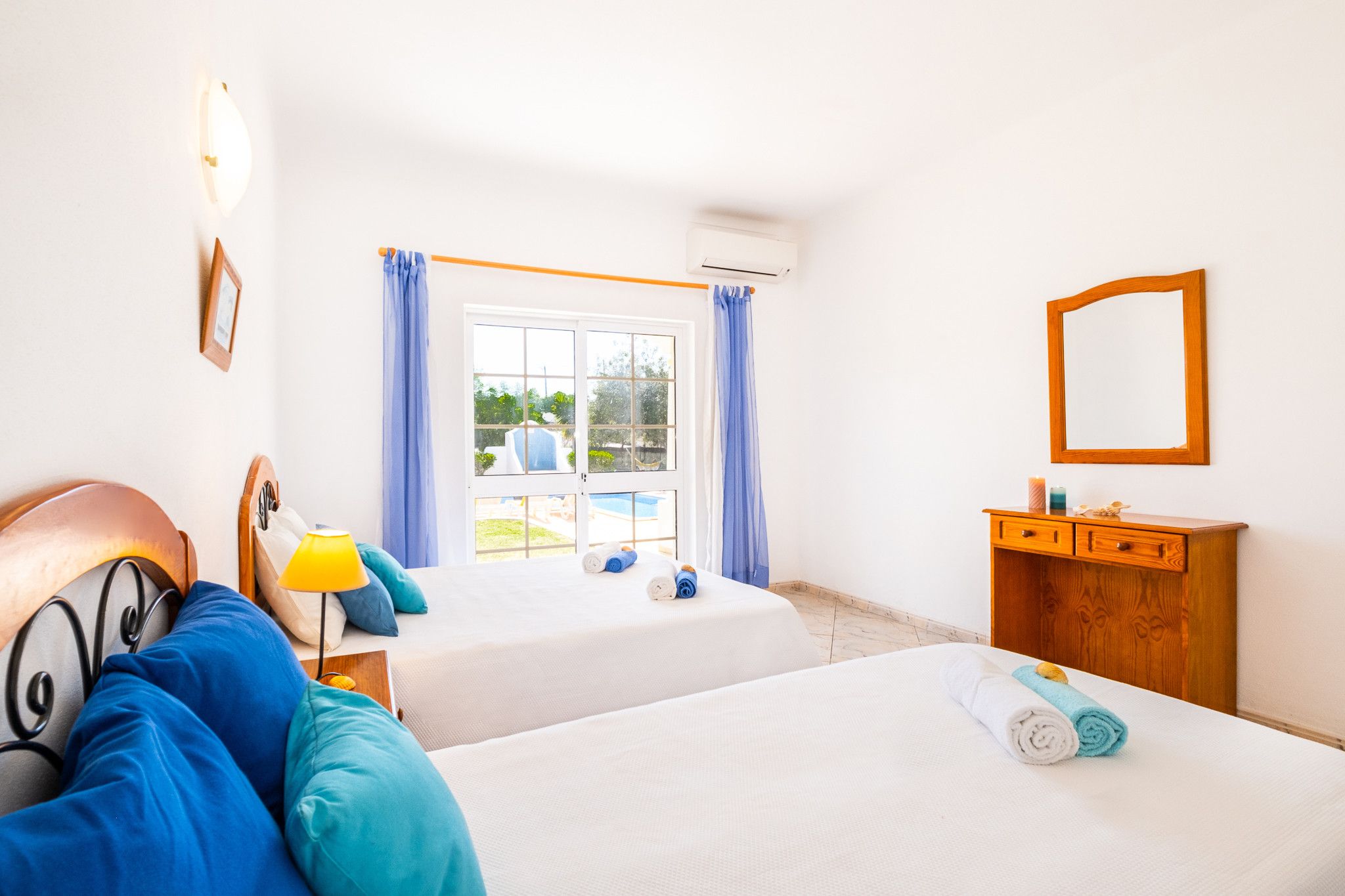 Une chambre d’hôtel avec deux lits, une commode en bois, un miroir et une fenêtre avec des rideaux.