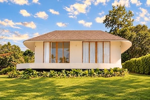 A modern house with a curved roof, large windows, and a well-maintained lawn.