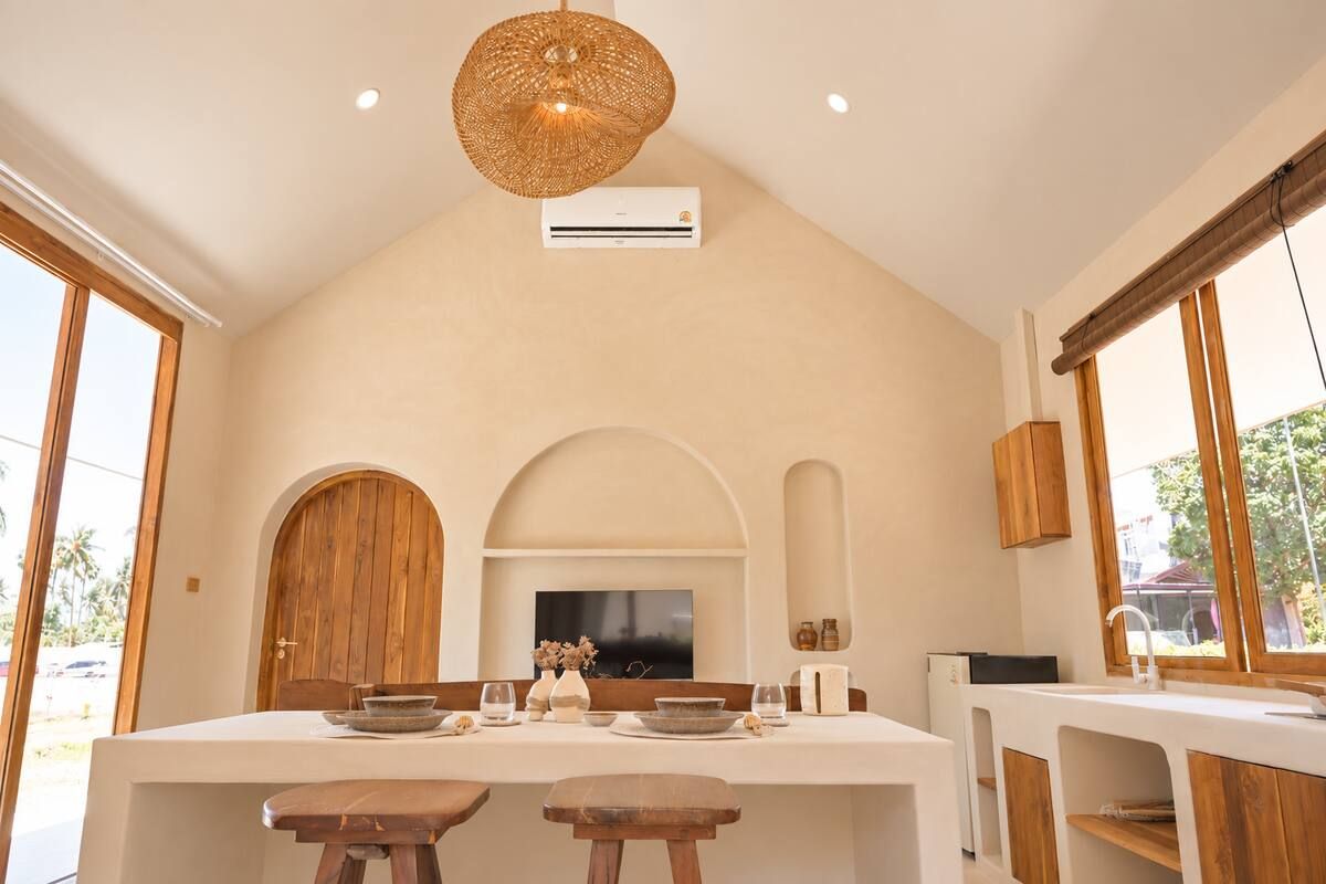 Una cocina moderna con una isla central, armarios de madera y un ventanal grande.