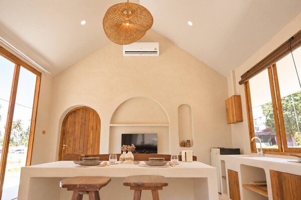 A modern kitchen with a central island, wooden cabinets, and a large window.