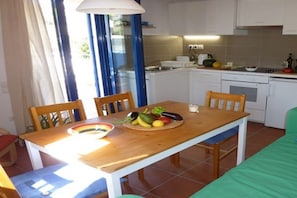 Una cocina compacta con armarios blancos, una mesa de madera y un frutero.