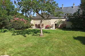 A stone building with a grassy yard, a tree, and a flower bed. - Holiday home with 2 bedrooms (Ste. Honorine des Pertes)
