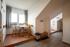 Un espace de vie compact comprenant un coin repas, une petite cuisine et un escalier menant à un autre niveau.
