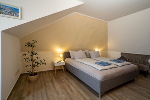 A bedroom with a bed, bedside lamps, a potted plant, and a view of a cityscape. - House on the lake shore (Waren)