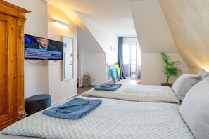 Une chambre d’hôtel avec deux lits, une télévision, une plante et une vue sur l’extérieur.