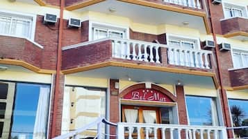 Ein mehrstöckiges Hotel mit Balkonen, einer Treppe und einem Schild mit der Aufschrift 'Bel Mar Hotel'.
