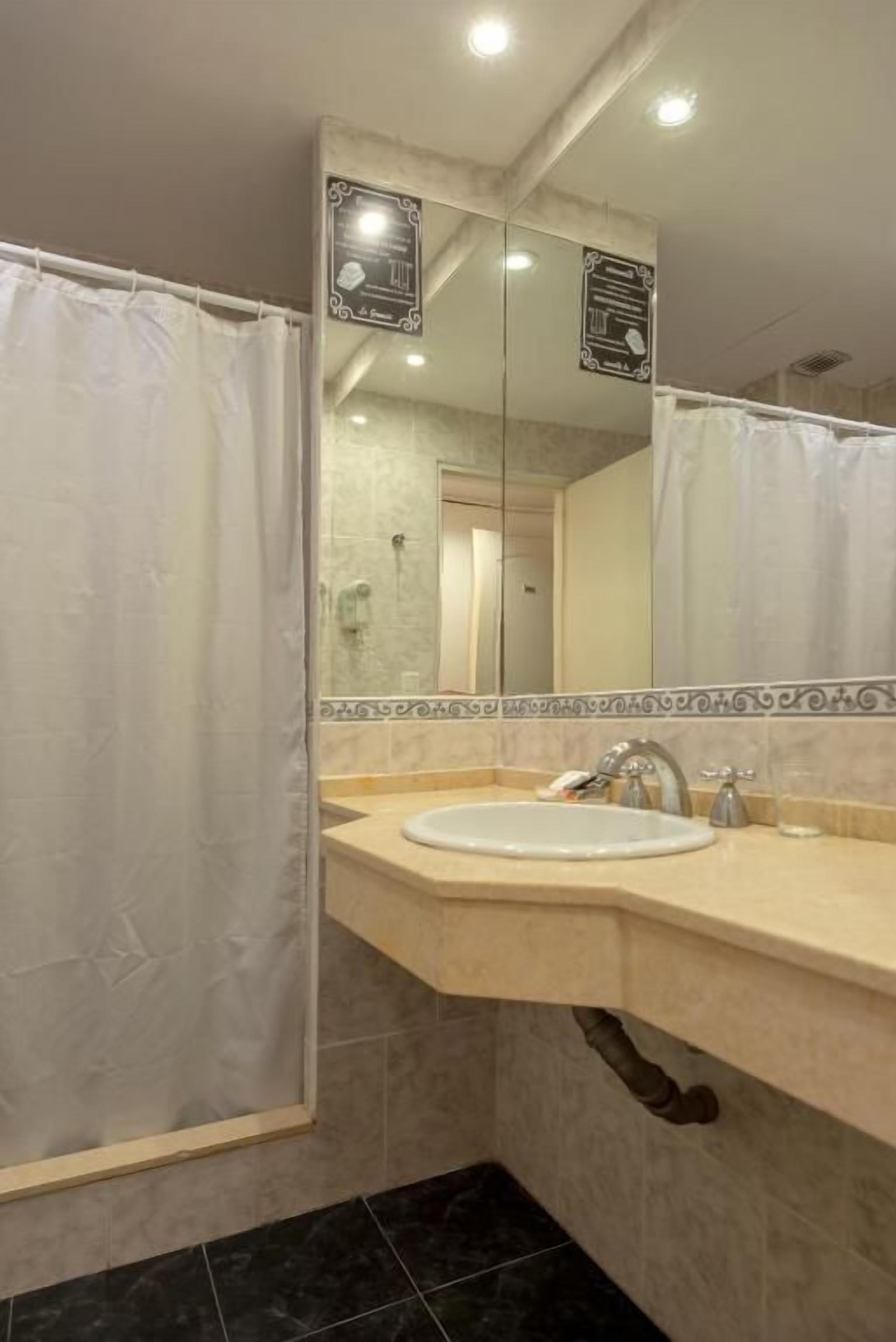 Un baño con lavabo, espejo y cortina de ducha.
