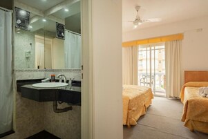 Una habitación de hotel con baño, cama y balcón.