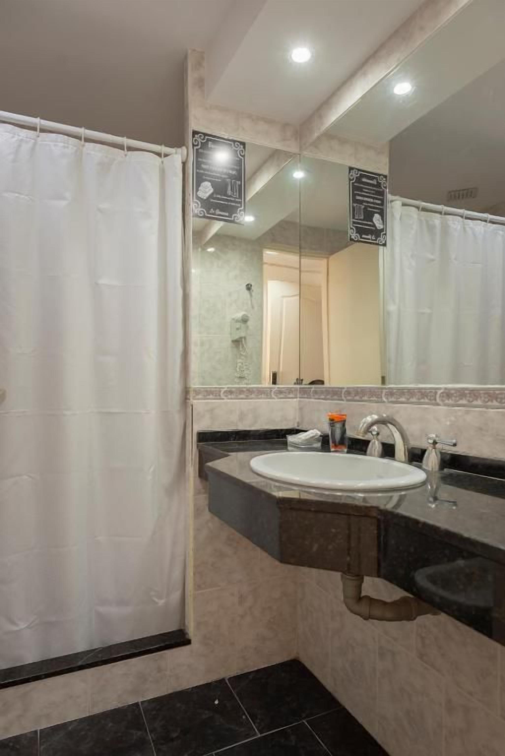 A bathroom with a shower curtain, a sink, a mirror, and a towel rack.