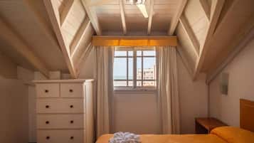 Una habitación de hotel con cama, cómoda, ventana con cortinas y ventilador de techo.