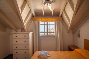 A hotel room with a bed, a dresser, a window with curtains, and a ceiling fan. - Hotel Belmar (Villa Gesell)