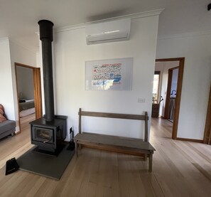 Ein Zimmer mit Kaminofen, einer Bank, einer Karte an der Wand und einer Tür zu einem weiteren Raum.