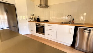A modern kitchen with stainless steel appliances, white cabinetry, and a wooden countertop.