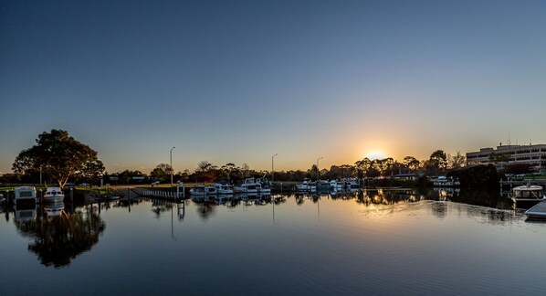A marina with boats docked, calm water, and a sunset in the background.