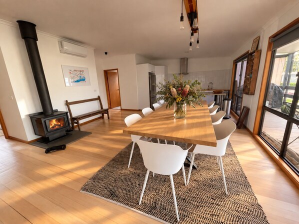 A modern kitchen with a central island, a built-in wood stove, and large windows.