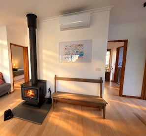 Een kamer met een houtkachel, een bank en een kaart aan de muur.