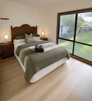 Una camera da letto con un letto grande, due comodini, un tavolino da notte e una finestra vista verde.