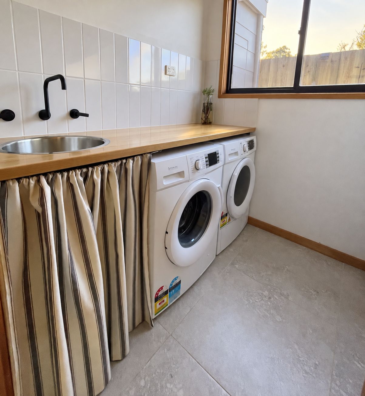A compact laundry area with a washing machine, a sink, and a window.