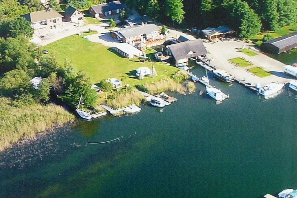 An aerial view of a lakeside property with multiple boats docked, a marina, and residential buildings.