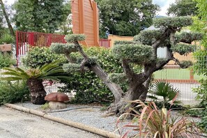 A well-maintained garden with a variety of plants, including a bonsai tree, a large mushroom, and a palm. - Chalet à la maison camping club (Argeles sur mer)