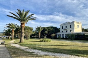 A building with a white facade and a balcony, surrounded by palm trees and a clear sky. - Chalet à la maison camping club (Argeles sur mer)